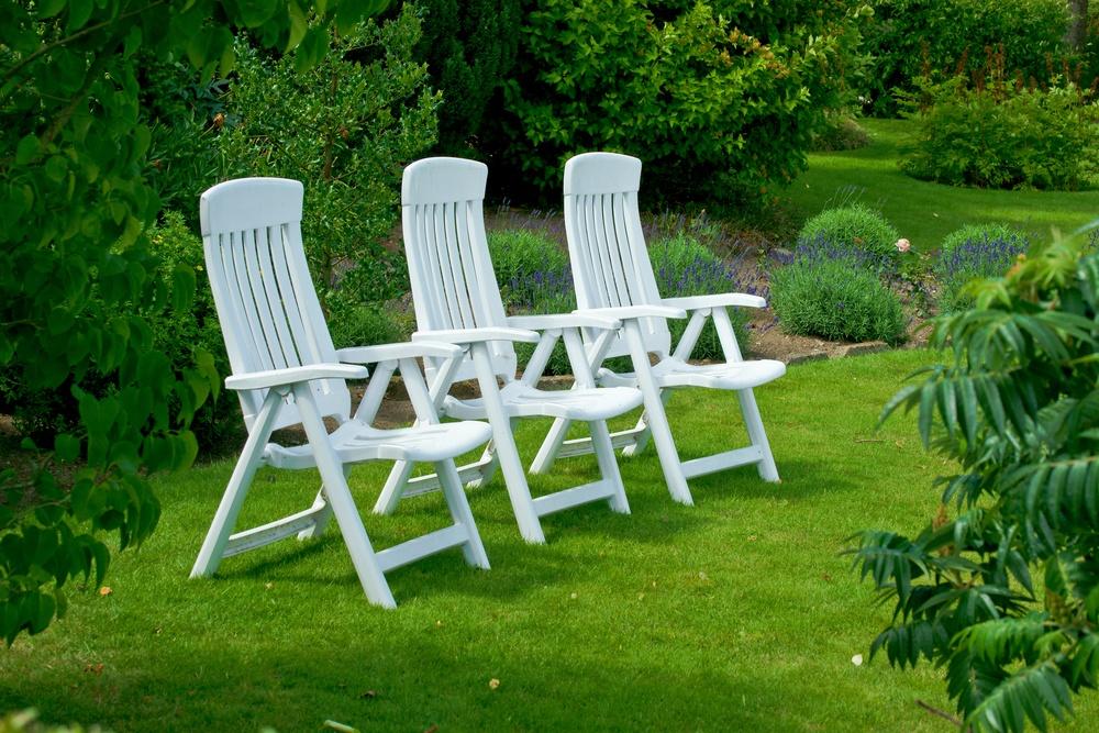 Белые садовые кресла на парковом газоне