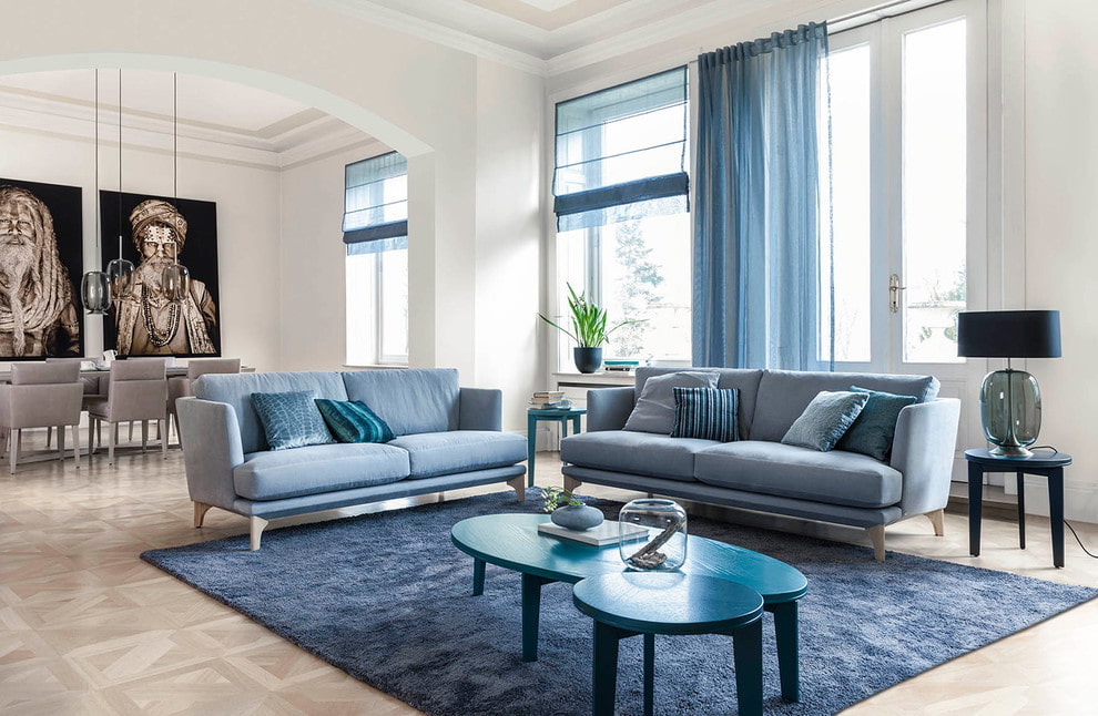 Два голубых дивана в гостиной с большими окнами