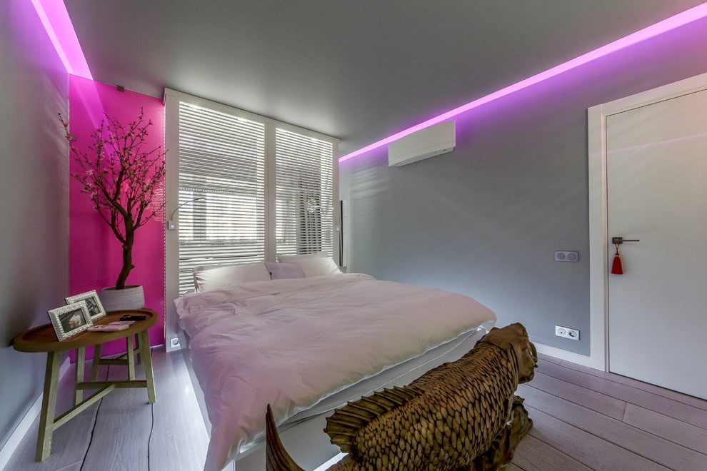 Розовая подсветка серой стены в спальне