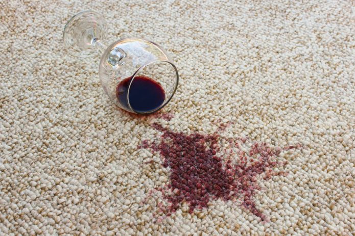 Бокал и разлитое вино на ковре