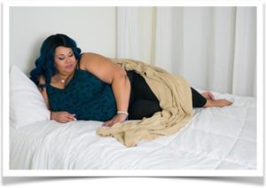 Крупная женщина лежит на кровати